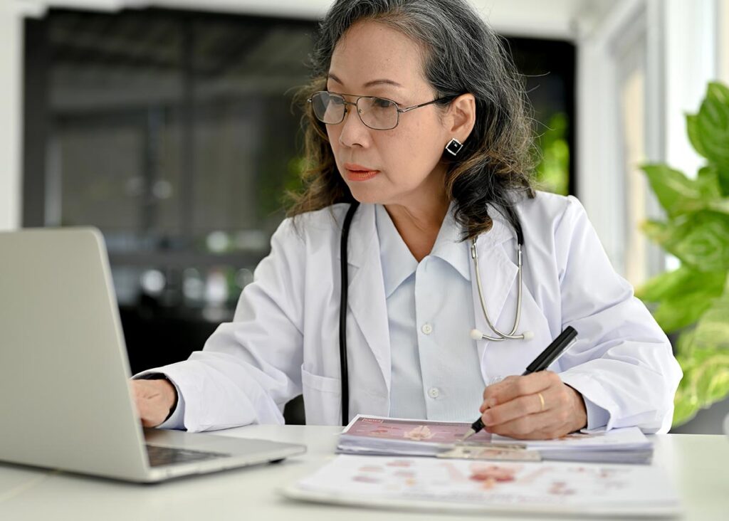 A healthcare professional works on a laptop