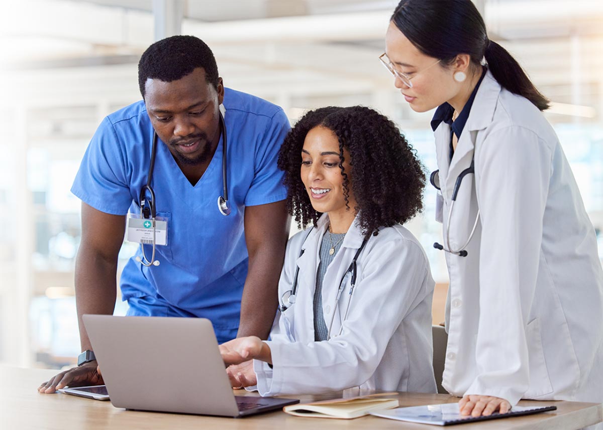 Group of healthcare professionals in discussion and reviewing information on a computer