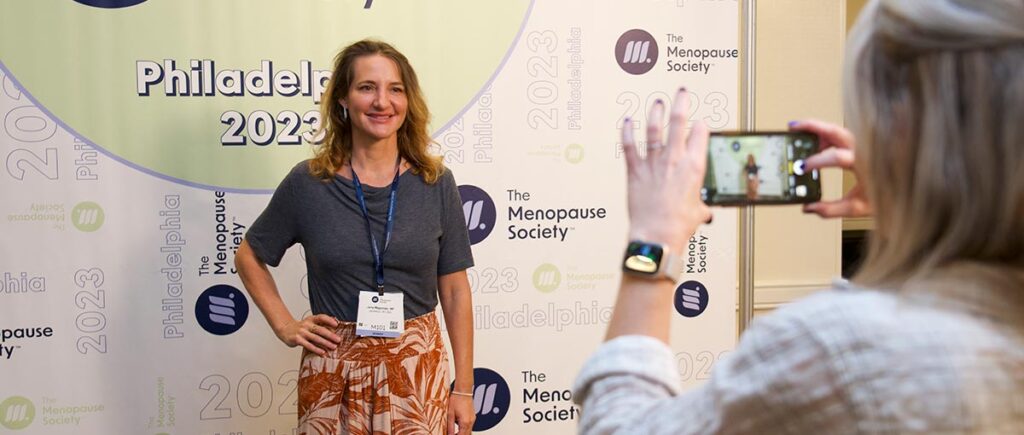 A woman take a picture with her phone of an event attendee