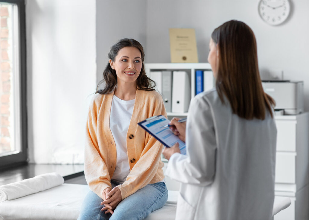 Female patient in an exam room with healthcare professional.