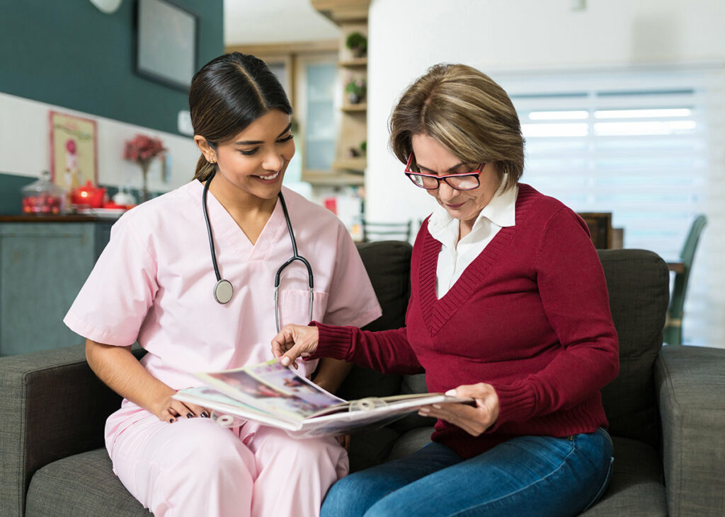 Healthcare professional sitting on a couch reviewing information with a female patient.