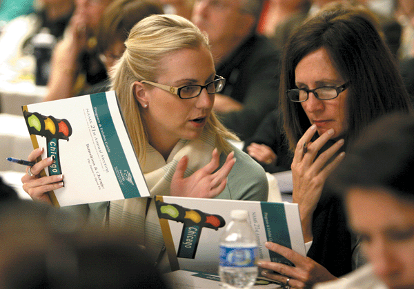 Two conference attendees discuss the conference agenda