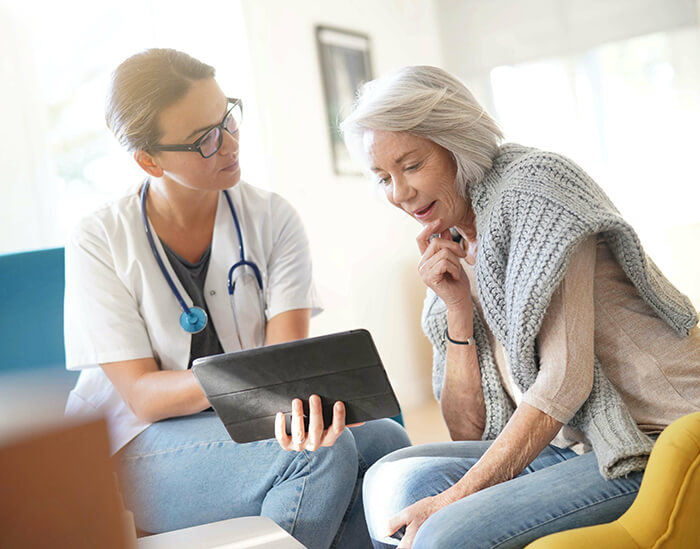 Patient seated reviewing information on tablet.