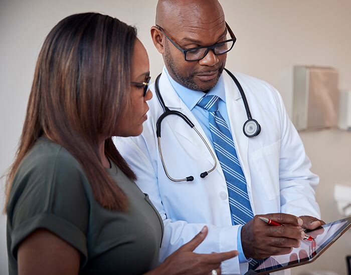 Healthcare professional standing showing information to patient.